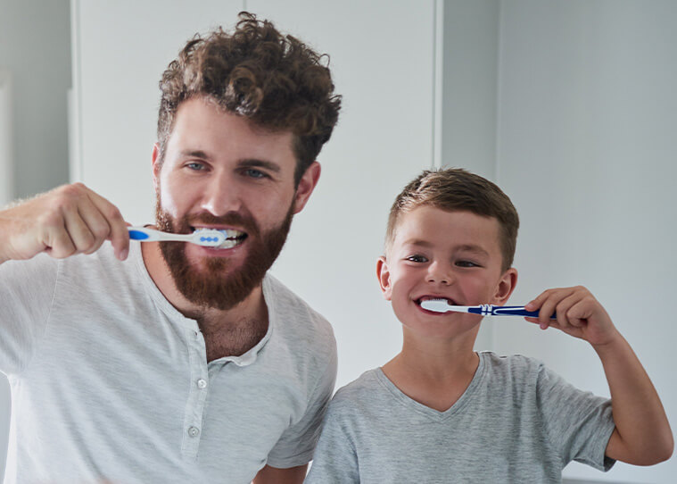 boy and his dad brushing their teeth